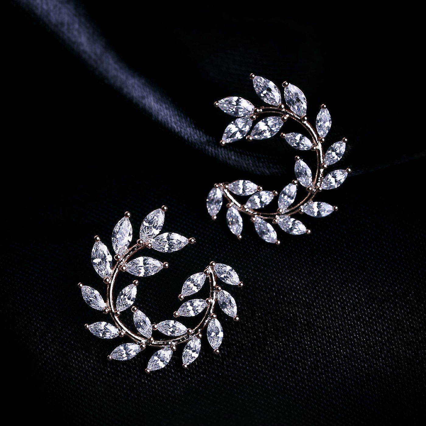 Pair of leaf-shaped diamond earrings on a black background