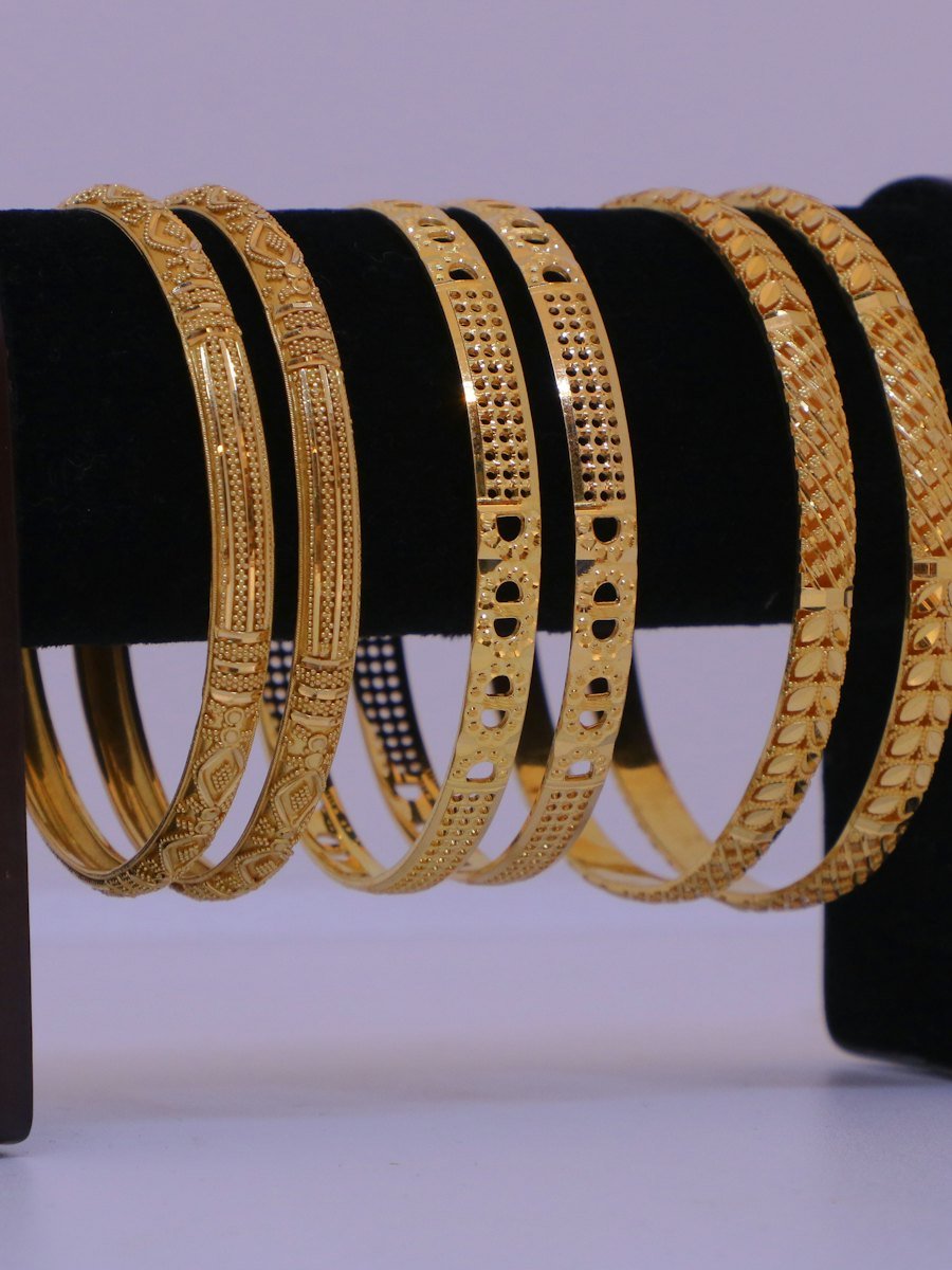 Set of gold bangles displayed on a stand