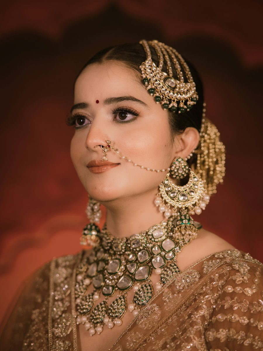 Woman wearing an ornate gold maang tikka, nath and bindi