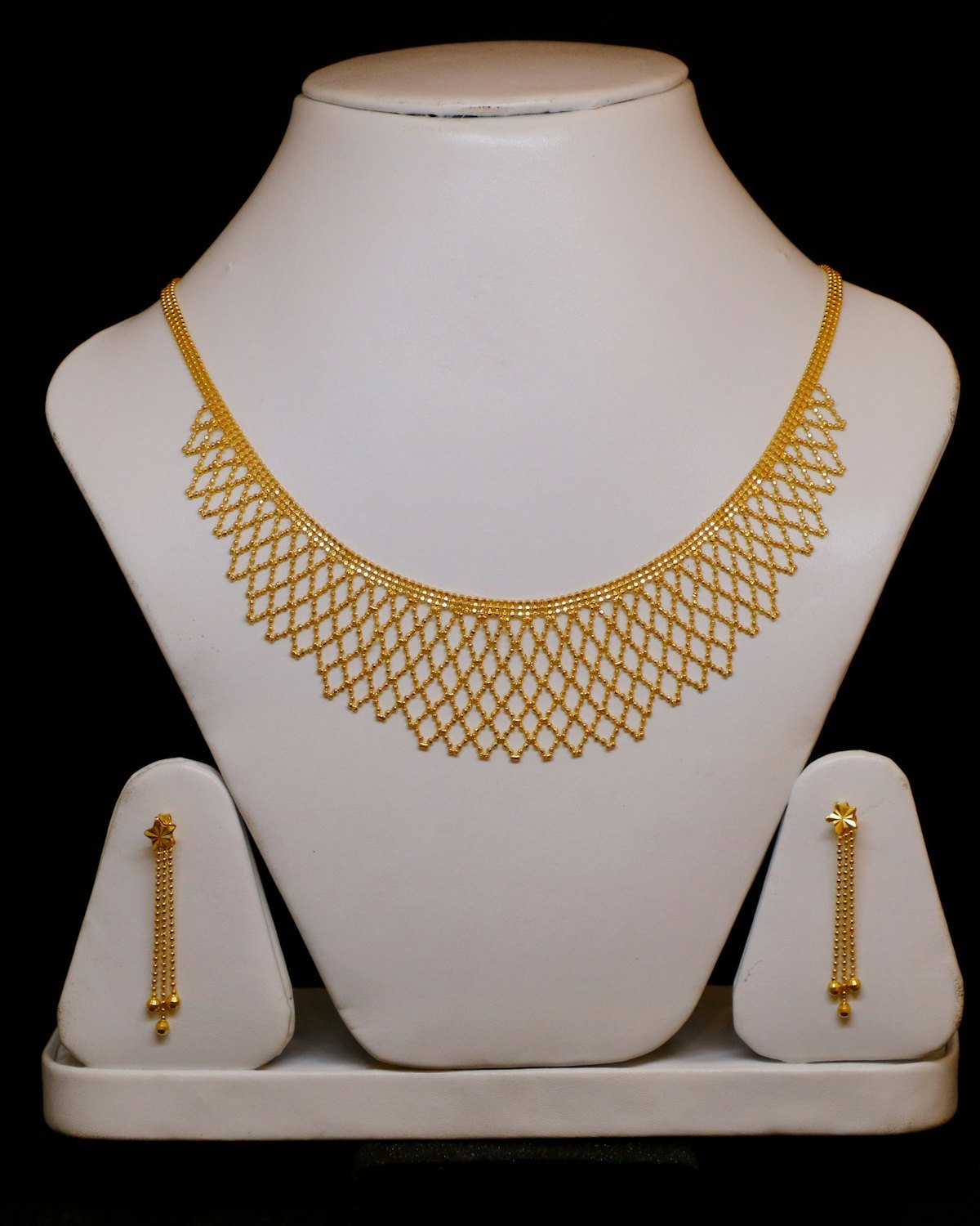 22kt gold necklace and matching earrings on a jewelry display