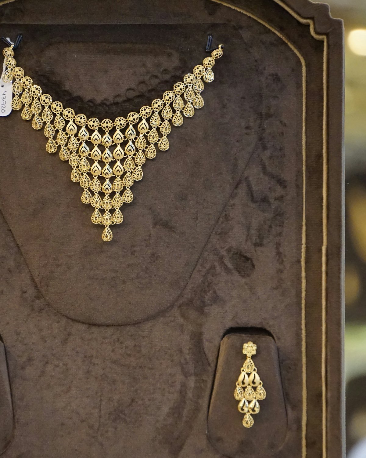 Gold necklace and earring set presented in a jewelry display case
