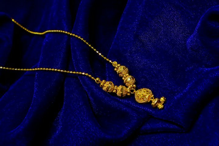 Gold necklace with intricate bead detail on blue velvet