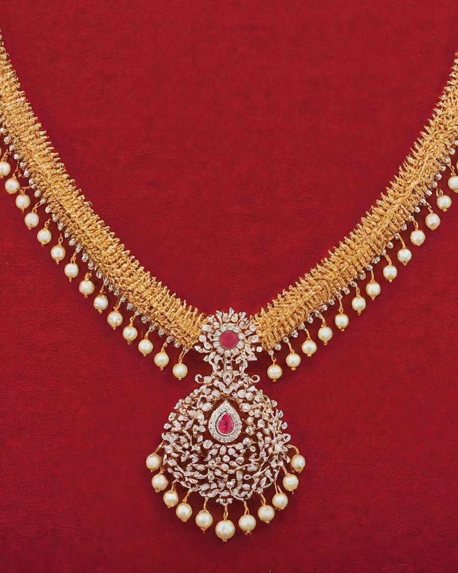 22kt gold necklace with pearl accents on a deep red background