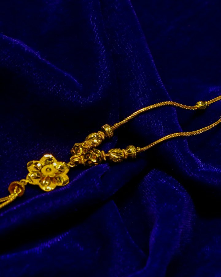 Gold floral pendant necklace on blue fabric
