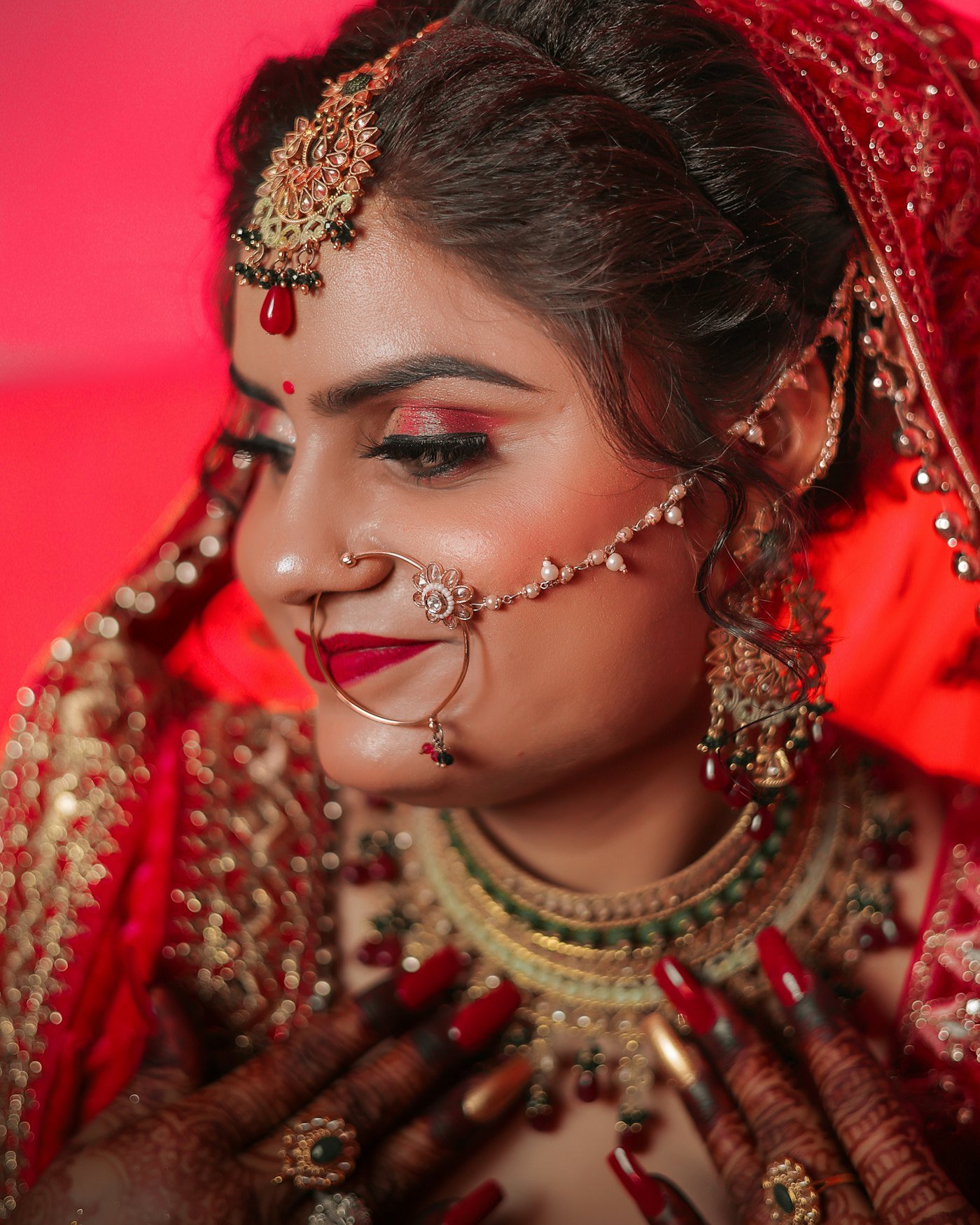 Bride in traditional red wedding attire wearing gold bridal jewelry
