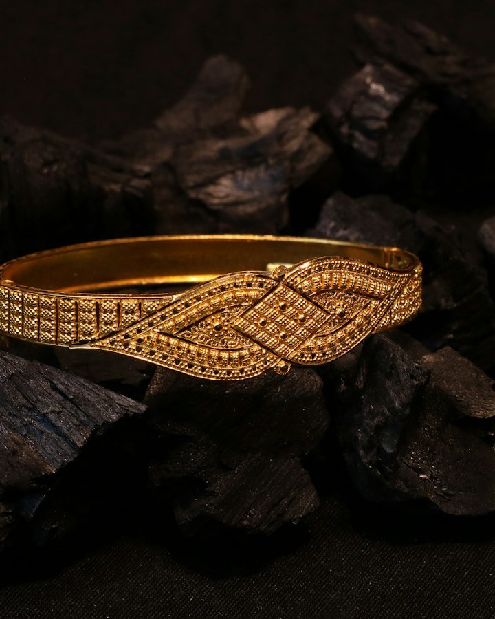 Ornate 22kt gold bangle resting on dark stone
