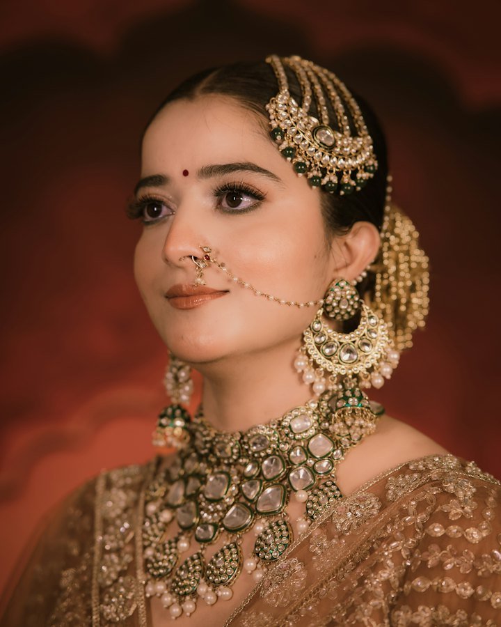 Woman wearing an ornate gold maang tikka, nath and bindi